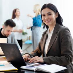 mulher com terno preto usando computador em um escritório com outras pessoas